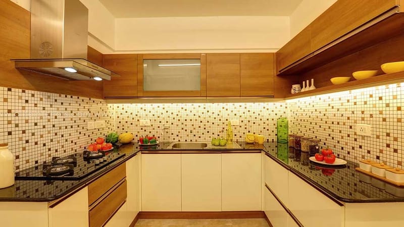L-shaped modular kitchen with mosaic-tile backsplash, wood and white cabinets, granite counter and chimney, Hyderabad