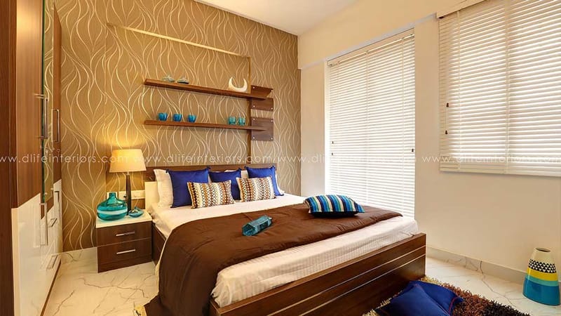 Bedroom with gold wavy-pattern feature wall, teal accents, floating shelves and brown-toned bed, Hyderabad
