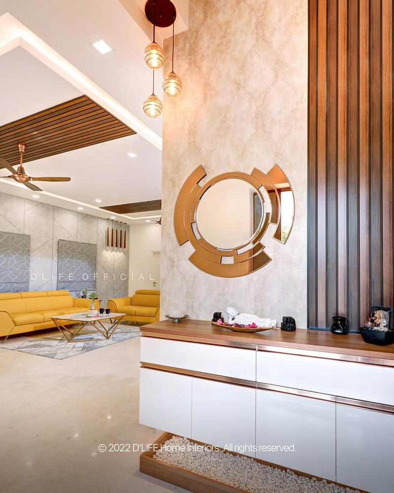 Entryway foyer with sculptural gold circular mirror, white console with wood trim and fluted wall panel, Hyderabad