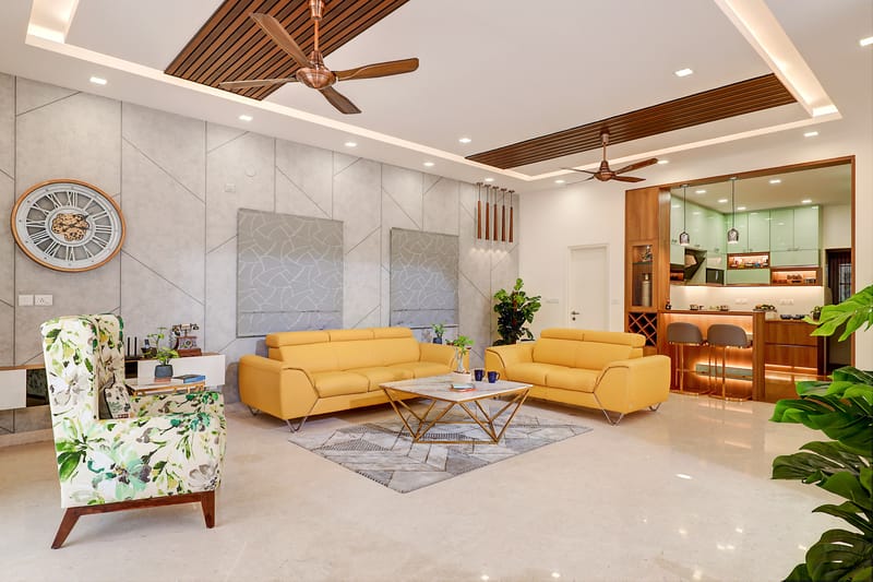 Spacious living room with two mustard leather sofas, floral accent chair, slatted wood ceiling and open kitchen view, Hyderabad