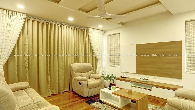 Living room with beige drapes, fabric sofa, leather recliner and wood TV panel over a wooden floor, Hyderabad