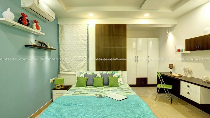 Bedroom with teal walls, green geometric bedding, white wardrobe and built-in study desk, Hyderabad