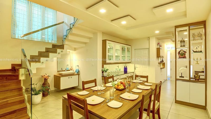 Open dining area with wood table set, glass-railed staircase, crockery unit and pooja niche in a Hyderabad home