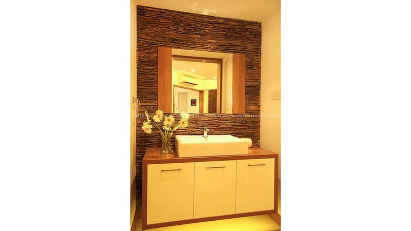 Washbasin vanity with vessel sink, wood-framed mirror and dark textured stone wall, Hyderabad