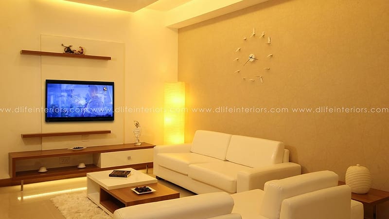 Living room with white leather sofas, wall-mounted TV unit, floor lamp and decorative wall clock, Hyderabad