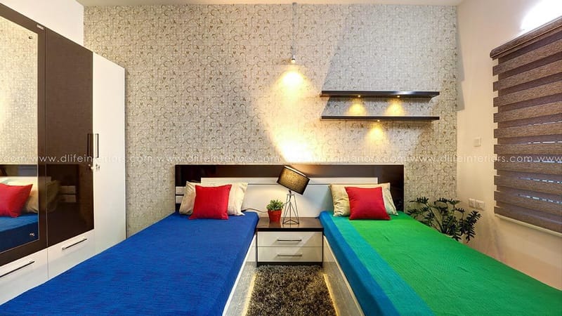 Kids' twin-bed room with patterned wallpaper, blue and green spreads, red pillows and lit niche shelf, Hyderabad