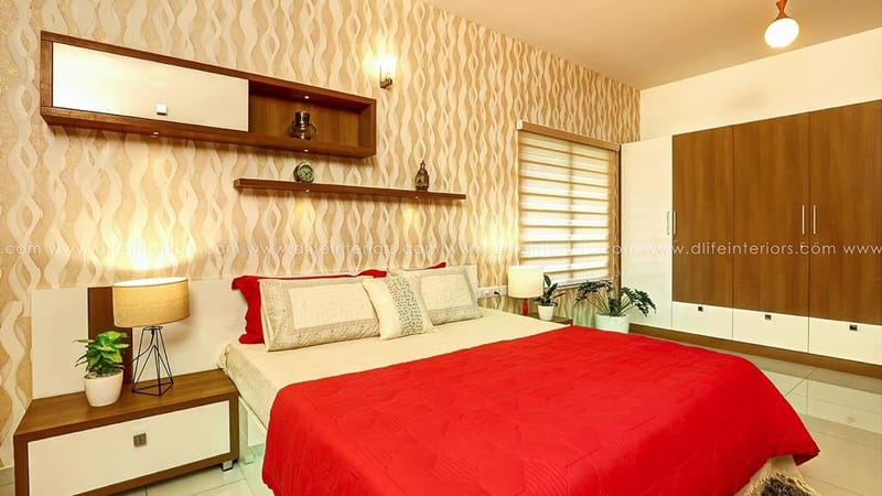 Bedroom in red and cream with patterned accent wallpaper, wood wardrobe and twin bedside lamps, Hyderabad