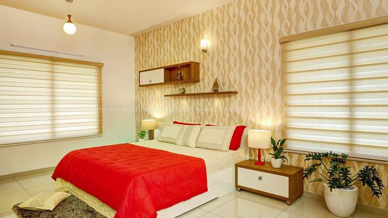 Bedroom with ripple-pattern wallpaper, red quilted bedspread, floating shelf and bedside lamps, Hyderabad