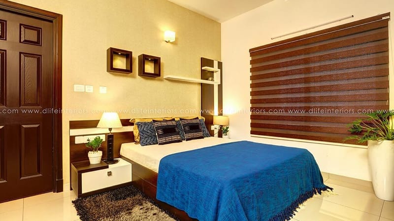 Bedroom with blue bedspread, dark timber blinds, wall niche shelves and a wood panelled door, Hyderabad