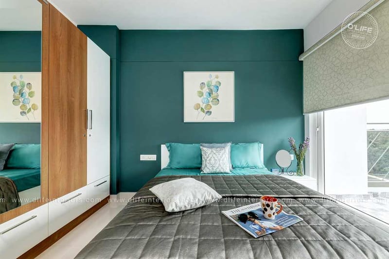Bedroom with deep teal feature wall, wood-and-white wardrobe, grey quilted bed and botanical prints, Hyderabad