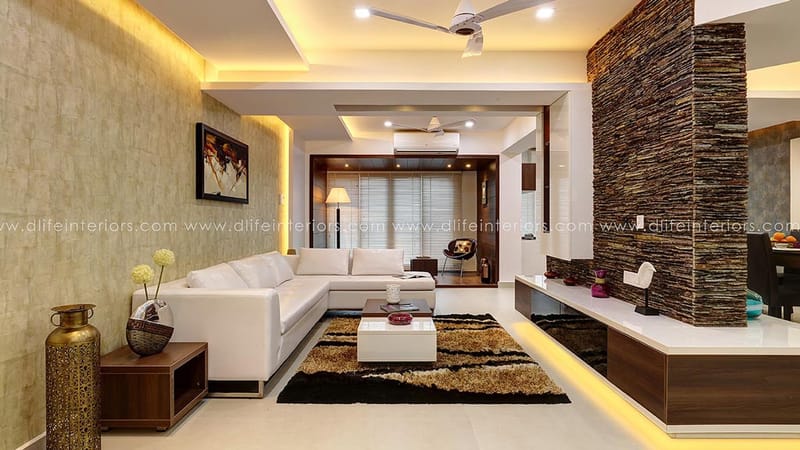 Living room in Hyderabad with white sectional sofa, dry-stone feature wall, shag rug and floating walnut TV console