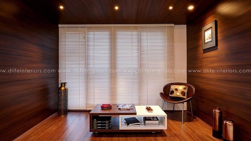 Sitting area with full wood-panelled walls, white venetian blinds, leather sling chair and low storage table, Hyderabad