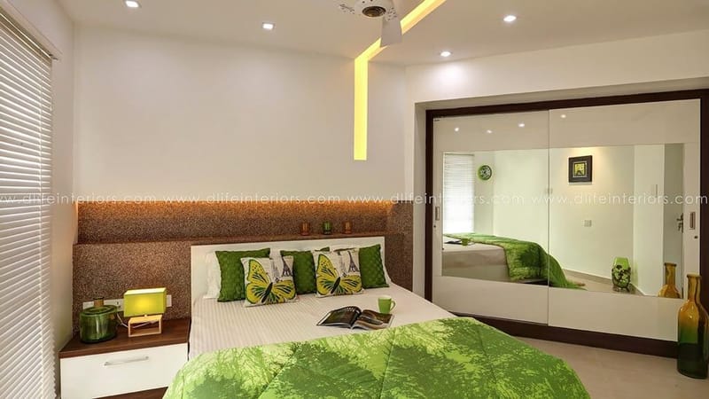 Bedroom in Hyderabad with green bedspread, mirrored sliding wardrobe, backlit headboard and recessed false ceiling