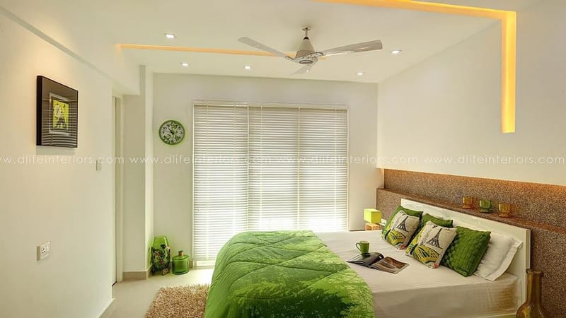 Bright bedroom with green leaf-print bedding, cork upholstered headboard, venetian blinds and yellow-lit false ceiling, Hyderabad
