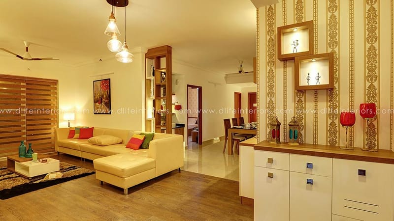 Warm-lit living room with cream L-shaped sofa, gold damask wallpaper feature wall and wood-slatted partition, Hyderabad