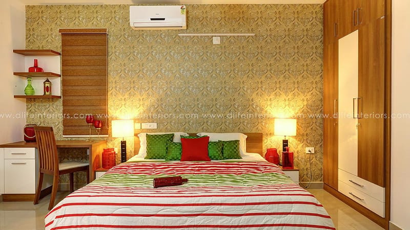 Bedroom with golden damask accent wall, twin bedside lamps, green-and-red cushions and corner study desk, Hyderabad