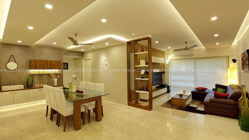 Open-plan living and dining with glass dining table, wooden display partition and brown leather sofa, Hyderabad