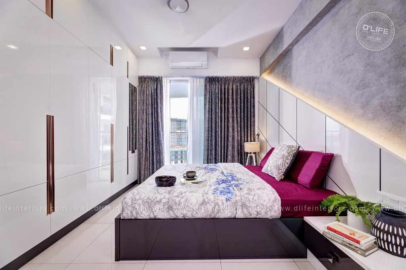 Bedroom with glossy white wardrobes, magenta upholstered bench and a grey textured headboard wall lit by warm LED, Hyderabad