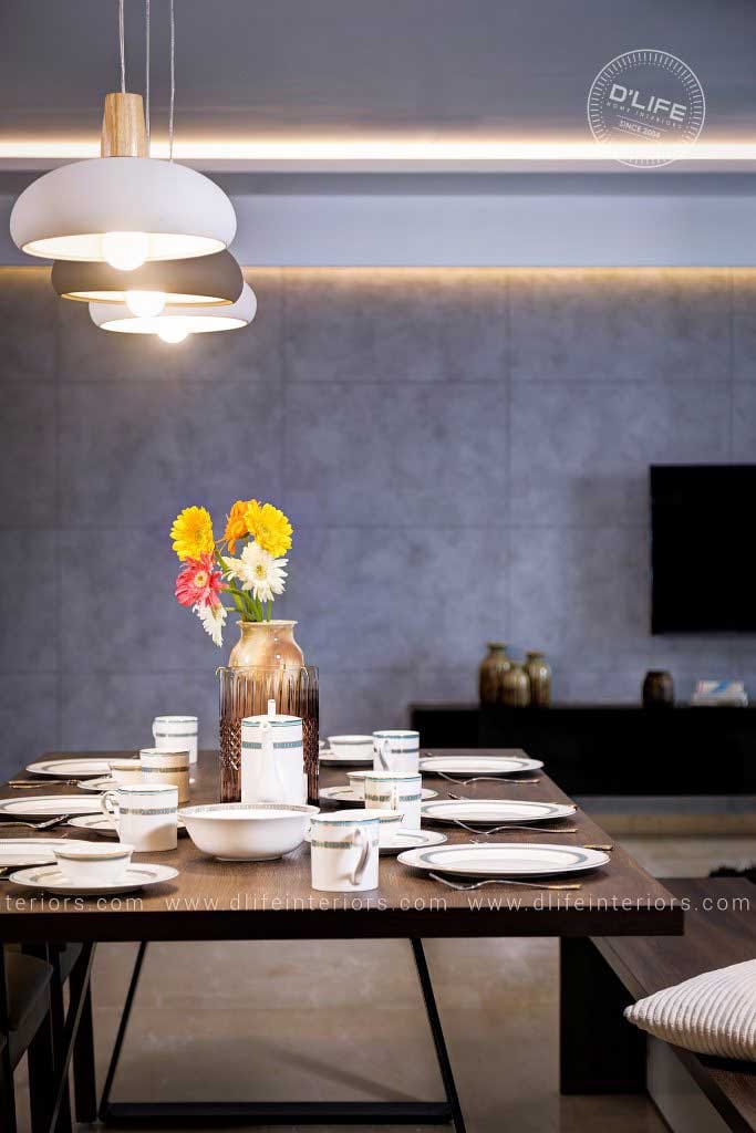 Laid wooden dining table with sculptural dome pendants, fresh flowers and white crockery against a grey accent wall