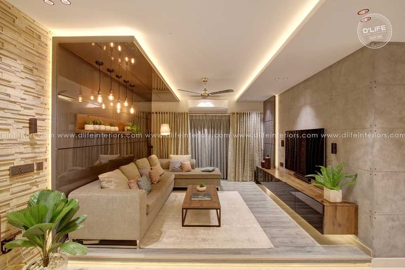 Living room in Hyderabad with beige sectional, cove-lit false ceiling, textured stone wall and wood TV console