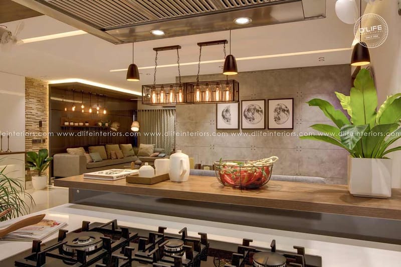 Open kitchen island with gas hob, caged pendant lights and a concrete feature wall with framed prints, Hyderabad