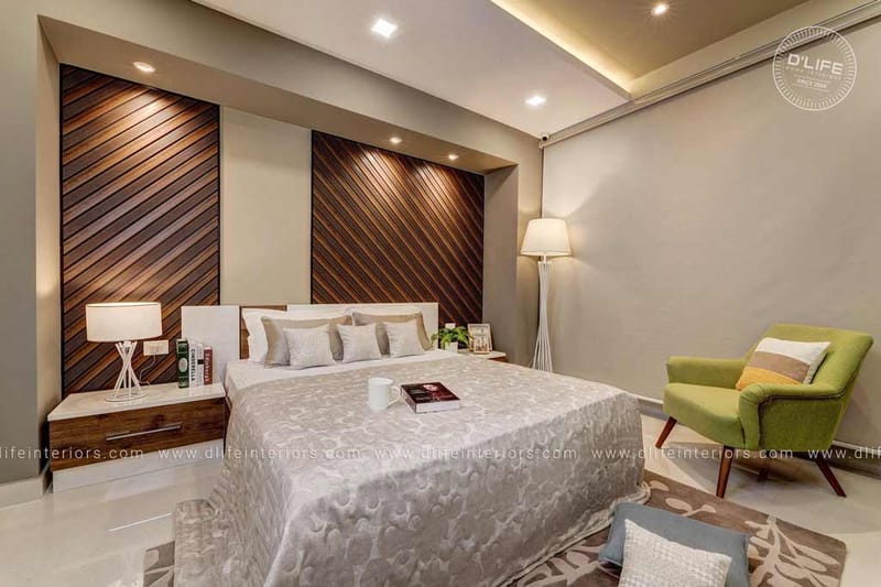 Bedroom with diagonal wood-slat headboard wall, white double bed and a lime-green tub chair, Hyderabad