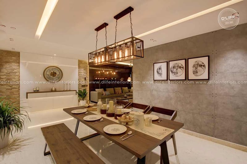 Dining area in Hyderabad with rustic wood table and bench, caged pendant light and lunar prints on a concrete wall