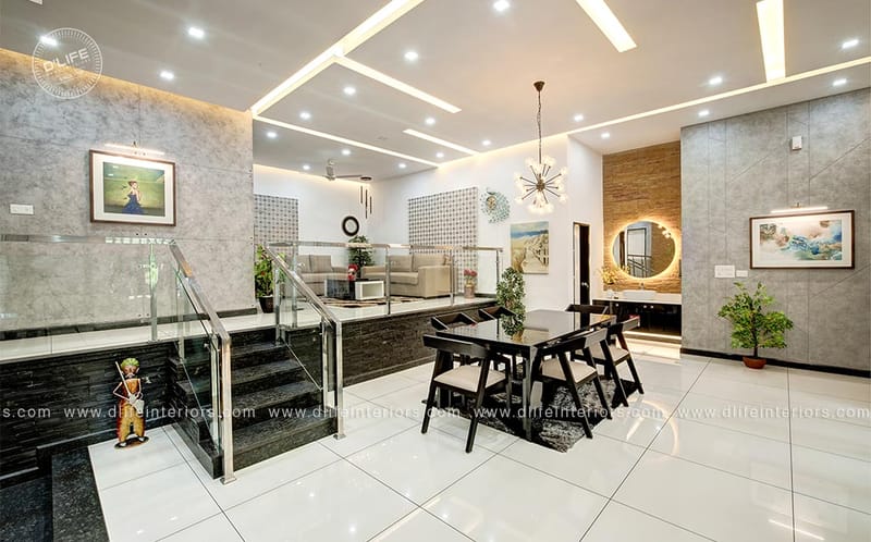 Open foyer and dining area with black-table seating, glass-railing staircase, sunburst chandelier and marble floors, Hyderabad