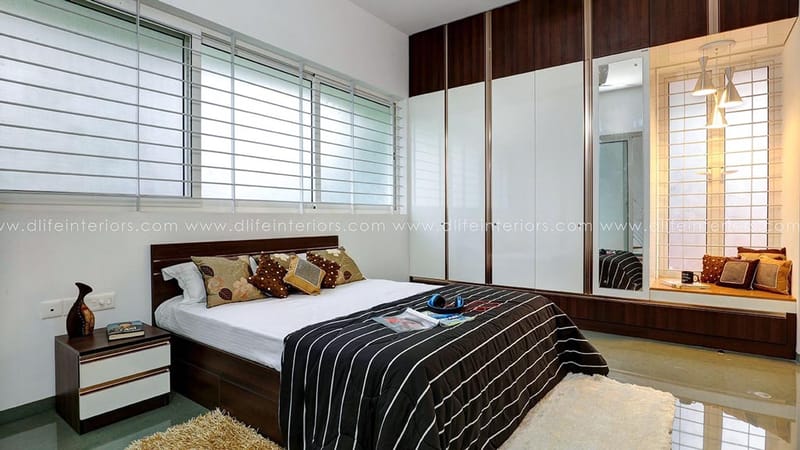 Bedroom with dark-and-white sliding wardrobe, mirrored panel, striped duvet and louvred windows, Hyderabad