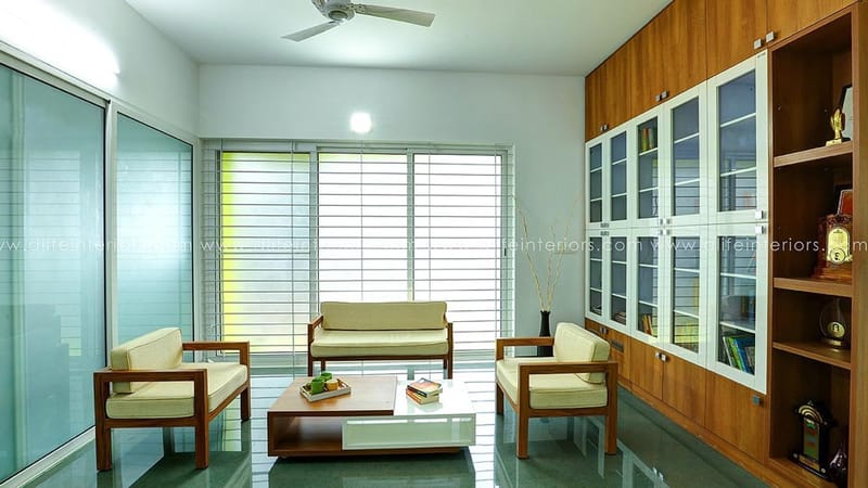 Living-study room with glass-front teak bookshelf wall, wooden sofa set and glossy green floor, Hyderabad