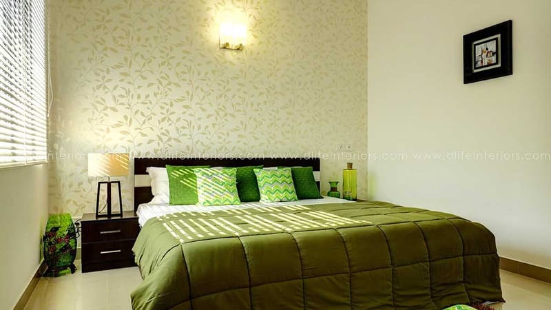 Bedroom with vine-motif feature wallpaper, olive bedding, dark headboard, bedside lamp and framed art, Hyderabad
