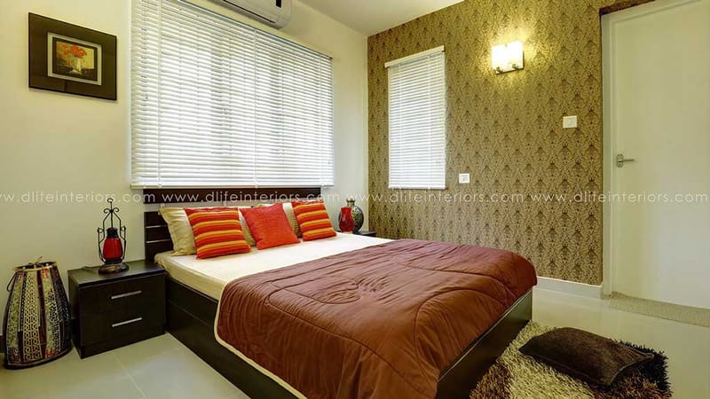 Bedroom with gold damask wallpaper, dark wood bed, orange bolster cushions and white window blinds, Hyderabad