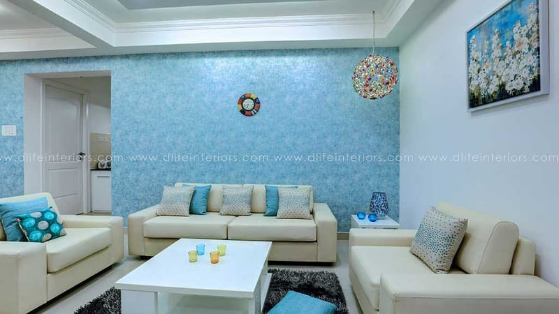 Living room in Hyderabad with blue textured wall, cream sofa set, beaded pendant globe and floral painting