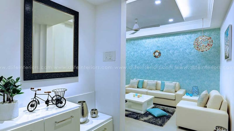 Entry console with black-framed mirror and decor bicycle opening to teal-walled living room, Hyderabad home