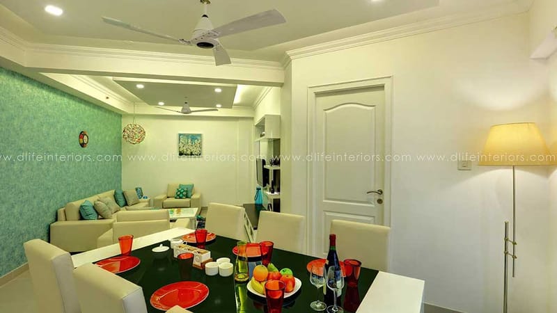 Open dining and living space with teal textured accent wall, white panelled door and set dining table, Hyderabad full home