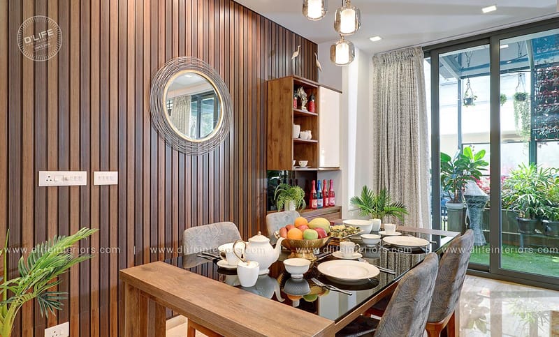 Dining area with glass-top wood table, grey chairs, round mirror and slatted wood wall, Hyderabad home