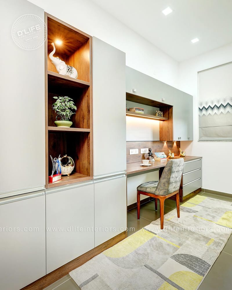 Study nook with floating wood desk, grey upholstered chair and warm-lit walnut display niche, Hyderabad home