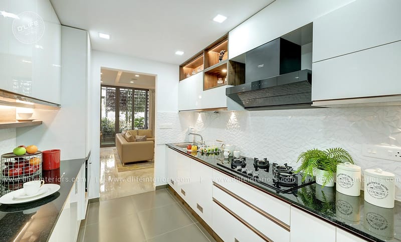 Parallel modular kitchen in glossy white with black granite counters, chimney and textured tile backsplash