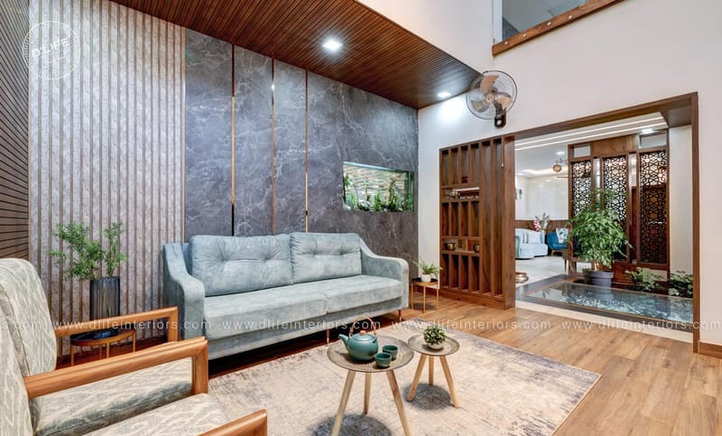 Living room with grey marble feature wall, wooden slat ceiling, grey sofa and round nesting tables, Hyderabad