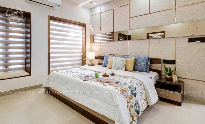 Master bedroom featuring a beige panelled wall with brass grid and mirror accents, blue and gold cushions, Hyderabad