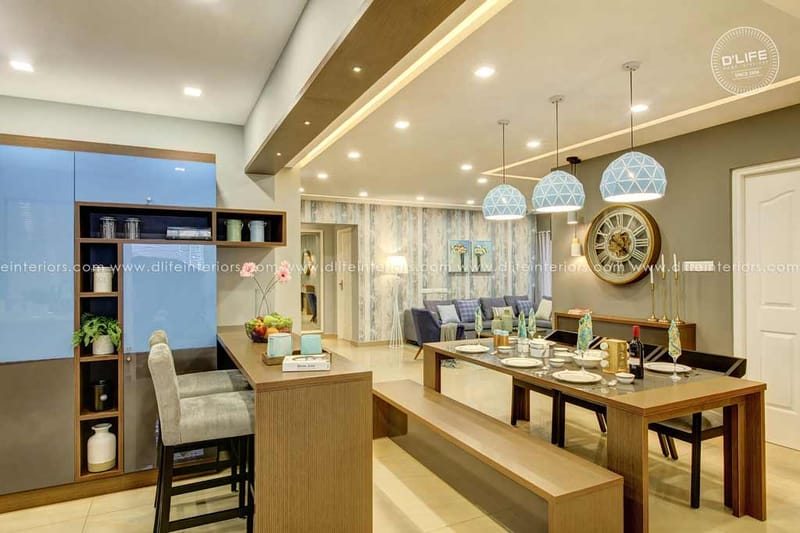 Open dining area with bench-seat wooden table, glass breakfast counter and pendant lights under a tray ceiling, Hyderabad
