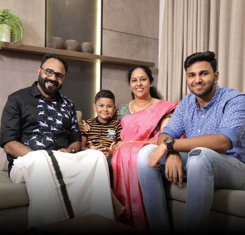 Family of four seated on a grey sofa in a living room with backlit niche and floating display shelf, Hyderabad