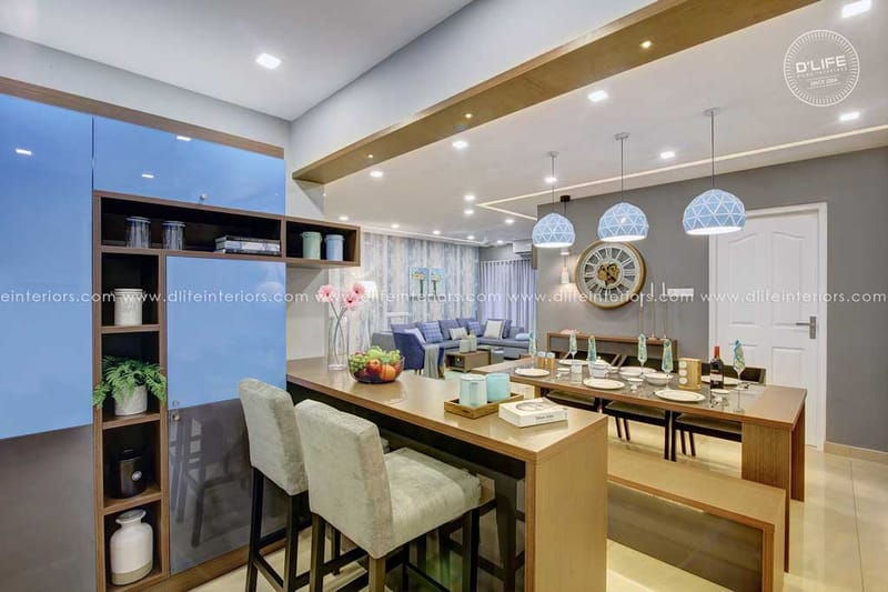 Breakfast counter with grey upholstered stools beside a dining table, blue glass cabinetry and a wall clock, Hyderabad