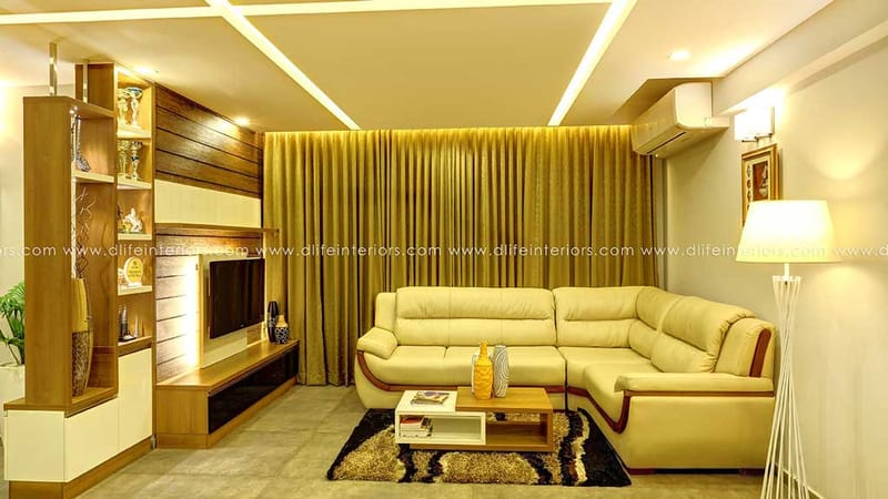 Living room with beige leather corner sofa, wood-panel TV unit, gold drapes and shag rug under a cove-lit ceiling, Hyderabad
