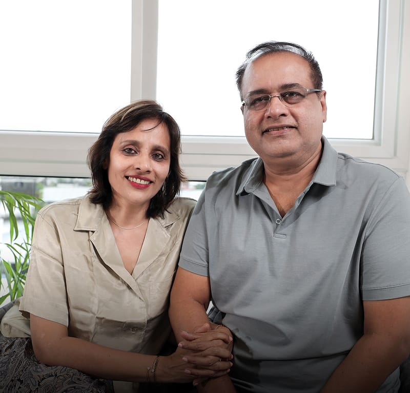 Smiling couple seated together by a bright window, client portrait for a Hyderabad full-home interior project