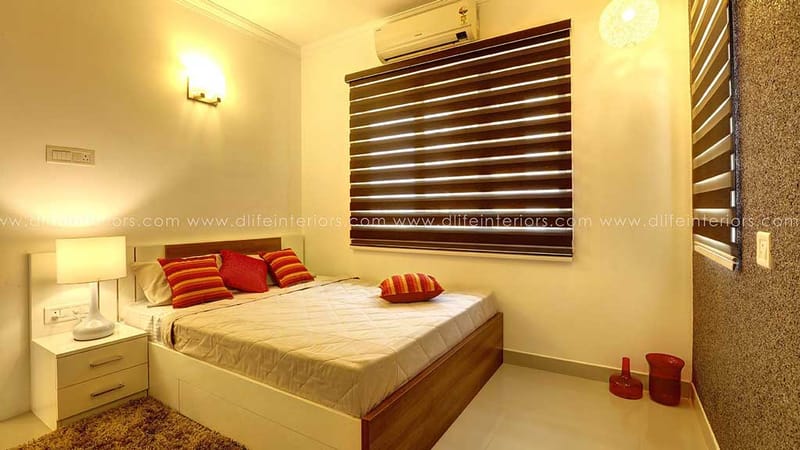 Cosy bedroom in warm amber light with orange bolster cushions, zebra blinds and a wood-trim bed, Hyderabad
