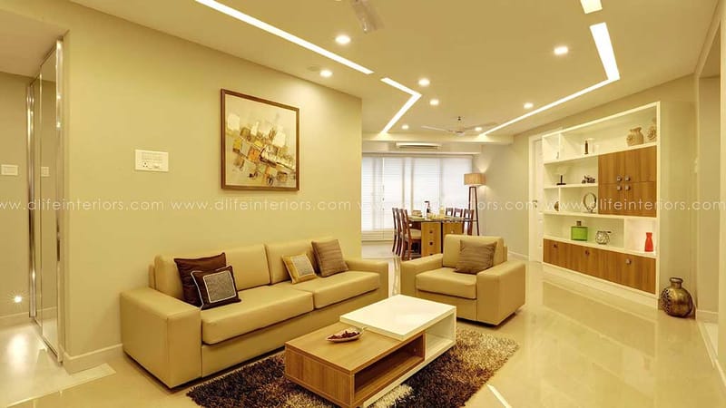 Living room with beige sofa and armchair, open wood shelving and dining space beyond, abstract art, Hyderabad