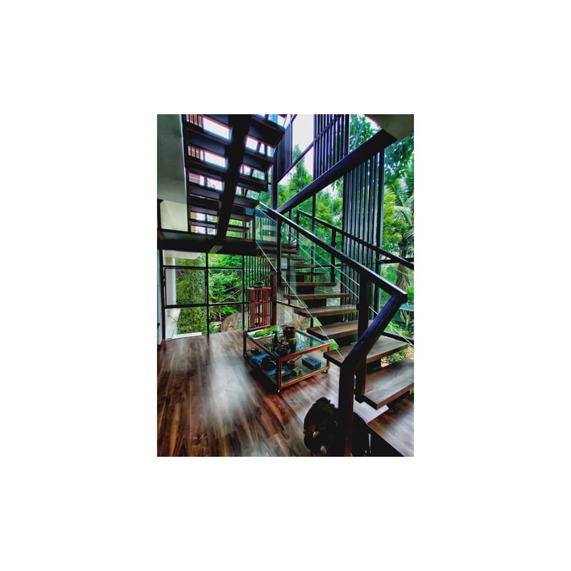 Industrial steel staircase with black metal balustrade, glass-walled landing and dark timber floor, Hyderabad home