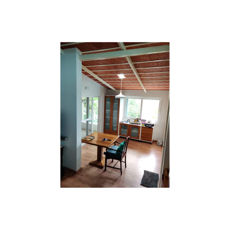 Dining area with exposed terracotta-tiled ceiling, wood table and glazed crockery cabinet beside a window, Hyderabad