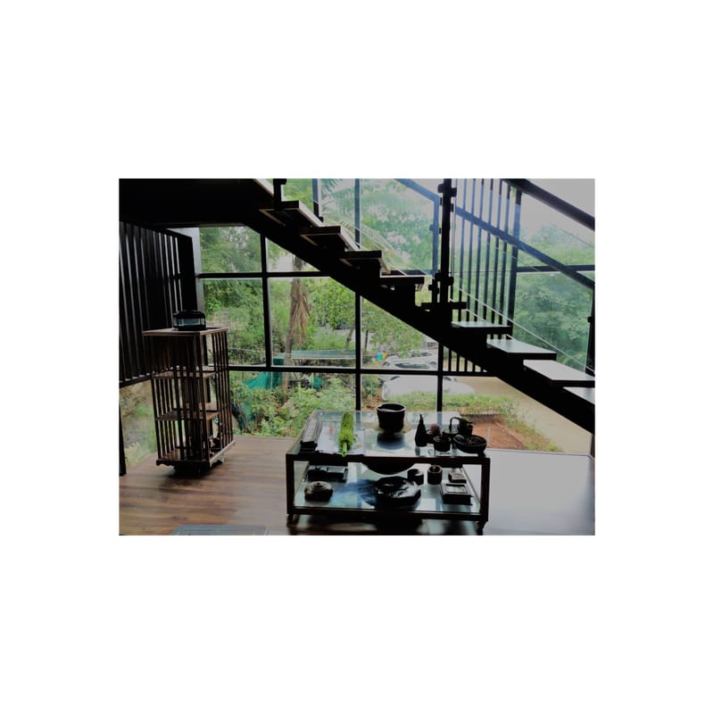 Stairwell seating nook with black metal stairs, full-height glass overlooking greenery and a styled console table, Hyderabad